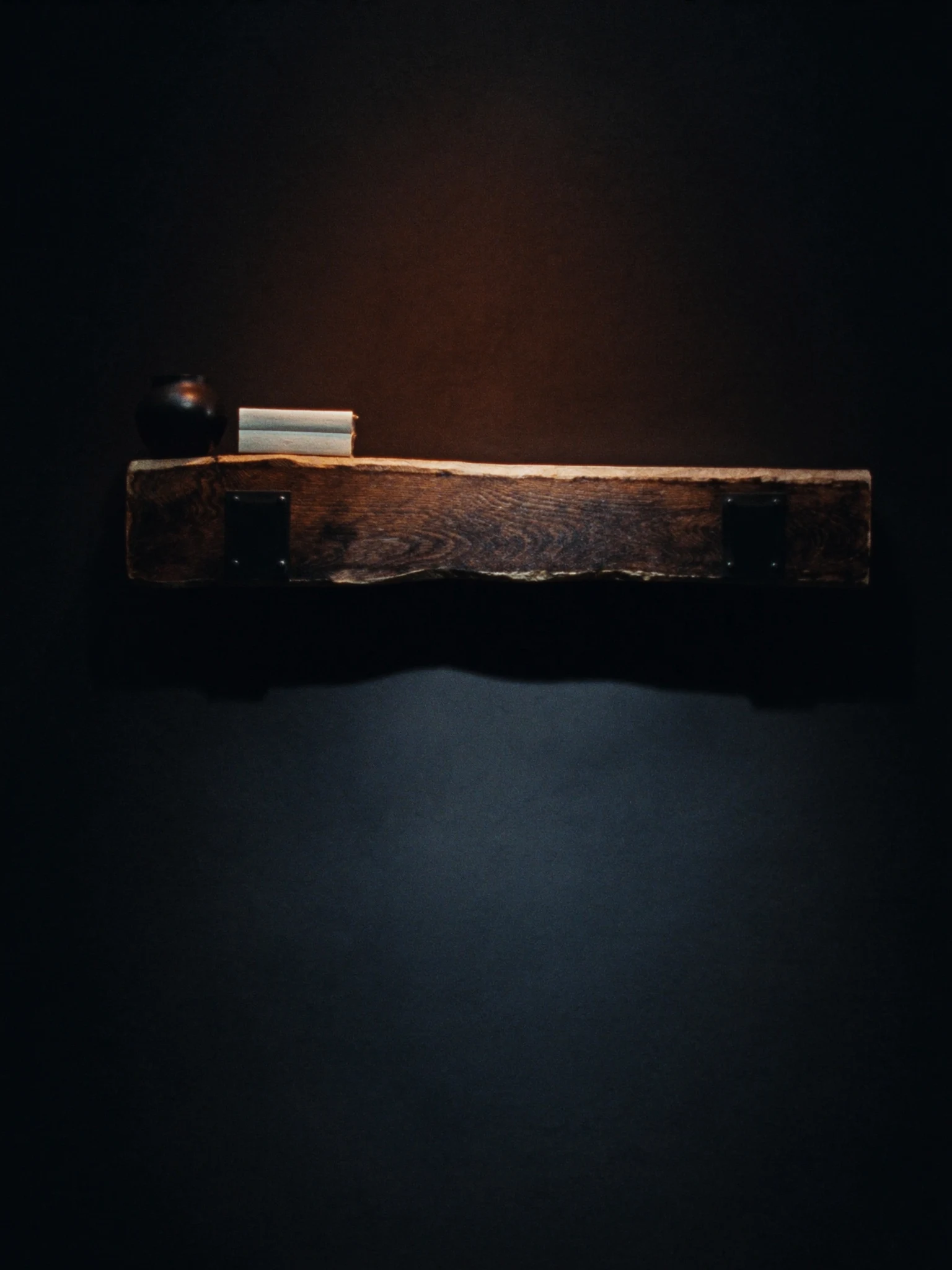 Illustrative solid reclaimed beam mantel against a dark wall